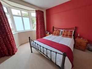 a bedroom with a bed with red walls and a window at Peaceful retreat / spacious bedroom / free parking in Brighton & Hove