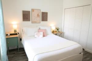 1 dormitorio con cama blanca y almohadas rosas en Clearwater Bohemian Escape - 7 min to the Beach, BBQ Grill, Playground, en Clearwater