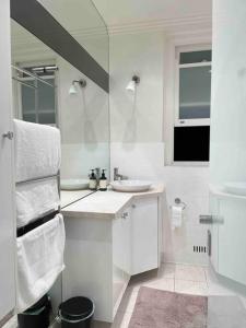 a white bathroom with a sink and a mirror at Stylish apartment in the heart of Potts Point in Sydney