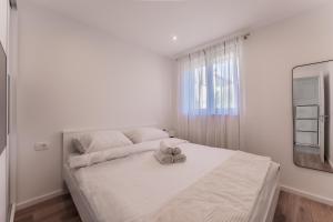 a white bedroom with a large bed and a window at Bernie apartments with a pool in Zadar +45 photos