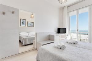 a white bedroom with two beds and a television at Hotel Caesar in Lido di Savio