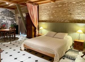 a bedroom with a bed and a table in a room at Chambres d'Hôtes Les Bournais - Le Clos Milady in L'Ile-Bouchard