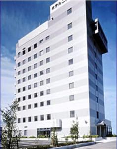 een hoog wit gebouw met een bord erop bij Hotel New Yutaka in Izumi-Sano