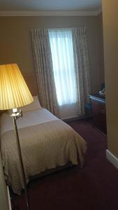 a bedroom with a bed with a lamp and a window at Hotel Sergul in London