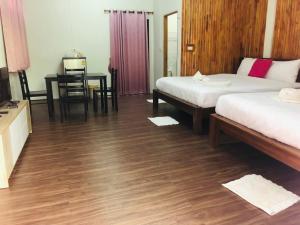 a room with two beds and a table and a desk at กอบสุข รีสอร์ท2 k04 in Ban Ton Liang