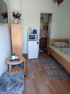 a small room with two beds and a table and a microwave at Szieszta Vendégház in Sárospatak