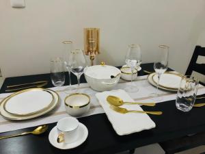 BGC Uptown 1 BR Condo في مانيلا: طاولة سوداء مع صحون بيضاء وادوات ذهبية