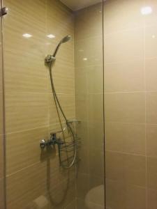 una doccia con porta in vetro in bagno di BGC Uptown 1 BR Condo a Manila