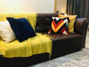 a brown couch with pillows and a yellow blanket at BGC Uptown 1 BR Condo in Manila
