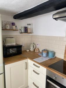 uma cozinha com armários brancos e um micro-ondas preto em Two Bedroom Cosy Character Cottage Sleeps 4 