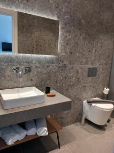 een badkamer met een wastafel, een toilet en een spiegel bij Bianco Hotel in Lakkíon