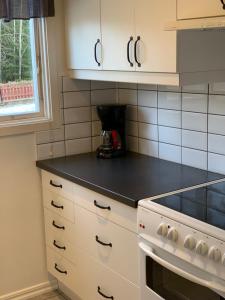 cocina con armarios blancos y encimera negra en Stuga i vassemåla en Vimmerby