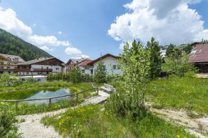 un pueblo con un estanque en medio de un campo en The Muse Apartments en Selva di Val Gardena