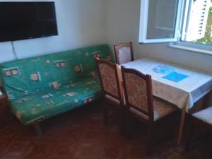 une salle à manger avec une table et un canapé vert dans l'établissement Apartmani Tereza, à Lumbarda