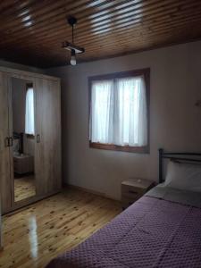 1 dormitorio con cama, ventana y espejo en Politis' wooden house, en Vasiliki