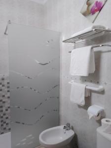 een badkamer met een wastafel, een toilet en handdoeken bij Hostal Los Arcos in Chipiona