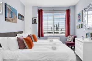 een slaapkamer met een groot wit bed en rode gordijnen bij Deco Seafront - By My Getaways in Brighton & Hove