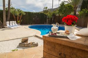 a pool with a table with a vase and flowers at Azul Rentals Villa Albir in Albir