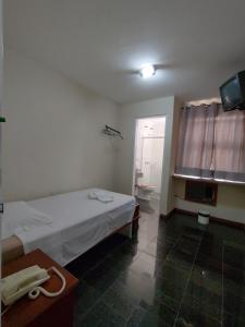 a room with a bed and a bathroom with a television at BIGS HOTEL in Penápolis