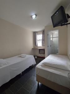 um quarto com duas camas e uma televisão na parede em BIGS HOTEL em Penápolis