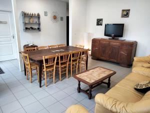 ein Wohnzimmer mit einem Tisch und Stühlen sowie einem TV in der Unterkunft Gîte de groupe 2 à 12 personnes in Guillon