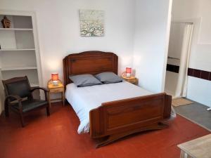 ein Schlafzimmer mit einem großen Holzbett und einem Stuhl in der Unterkunft Gîte de groupe 2 à 12 personnes in Guillon