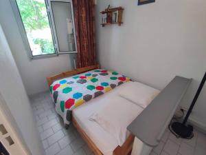 uma pequena cama num pequeno quarto com uma janela em Appartement familial, terrasse, piscine et parking em La Grande-Motte