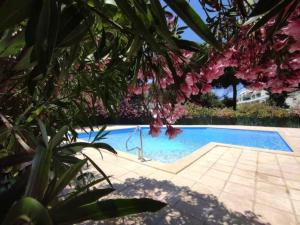 uma piscina num quintal com flores cor-de-rosa em Appartement familial, terrasse, piscine et parking em La Grande-Motte