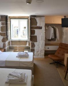 a bedroom with two beds and a window and a chair at Casa do Theatro Guest House in Barcelos