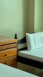 a bedroom with a bed and a wooden dresser at Inside Room Inn in Tagum