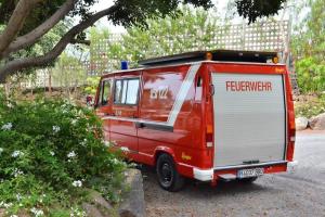 czerwony van zaparkowany przy drodze w obiekcie Conny, a Mercedes Firefighter Camper Van w mieście Los Cristianos