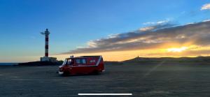 ロス・クリスティアーノスにあるConny, a Mercedes Firefighter Camper Vanの夕日の見える野原に停まった赤いバン