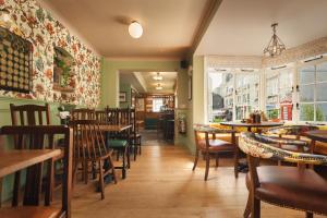 a restaurant with wooden tables and chairs and windows at The Rising Sun in Saint Mawes