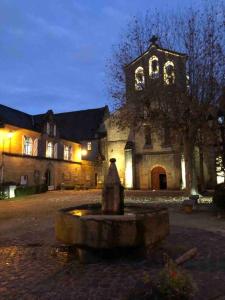 uma igreja com uma fonte em frente a um edifício em Maison O Vitraux - Sublime Maison - Joli bourg d'Aubazine em Aubazines