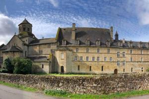 um grande castelo com uma parede de pedra e uma torre em Maison O Vitraux - Sublime Maison - Joli bourg d'Aubazine em Aubazines