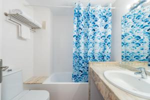 uma casa de banho com uma cortina de chuveiro azul e um lavatório. em Aparthotel Ferrer Lime Isabel em Cala Bona