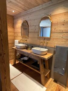 a bathroom with two sinks on a wooden wall at Alpen Charme - Chalet d'Hôtes et SPA in Gsteig