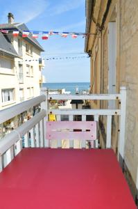 um banco numa varanda com vista para a praia em La Petite Baleine, appt à 50m de la plage em Luc-sur-Mer