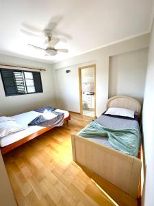 a bedroom with two beds and a ceiling fan at Apartamento 32 no centro de Águas de São Pedro in Águas de São Pedro