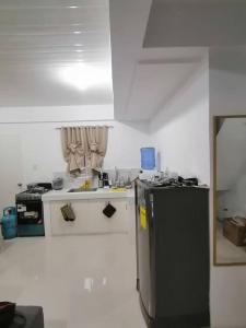 a small kitchen with a refrigerator and a stove at Full Aircon Camella House w/ wifi Netflix hotwater in Butuan
