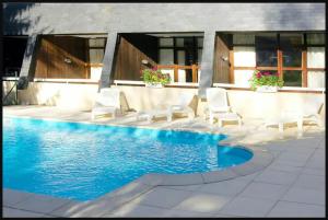 a swimming pool with white chairs next to a house at appartement 6 personnes proche commerce et remontés mécaniques in Saint-Lary-Soulan