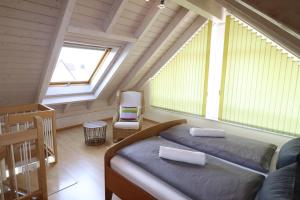 ウールディンゲン・ミュールホーフェンにあるGästehaus Mäder Am Hafenのベッドルーム1室(ベッド1台、屋根裏部屋の椅子付)