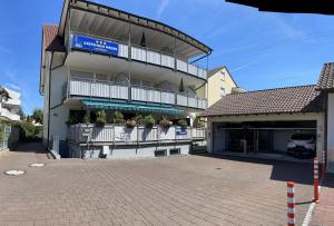 ein großes Gebäude mit Balkon und Parkplatz in der Unterkunft Gästehaus Mäder Am Hafen in Uhldingen-Mühlhofen