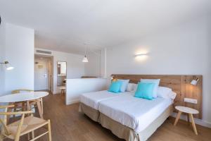 a bedroom with a bed with blue pillows and a table at Aparthotel Ferrer Lime Isabel in Cala Bona