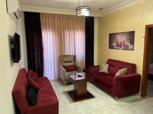 a living room with two red couches and a table at Suzan Hotel Apartments in Amman