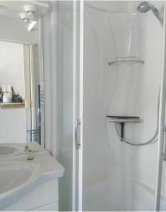 ein weißes Bad mit einer Dusche und einem Waschbecken in der Unterkunft PALAVAS STUDIO AVEC BALCON ET PARKING in Palavas-les-Flots