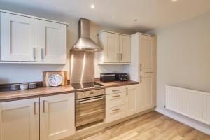 uma cozinha com armários brancos e um relógio no balcão em Host & Stay - Town House em Seaham