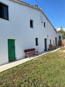 a white building with a green door and a bench at CAN MANYANA in Riudarenes