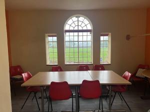 a meeting room with a table and red chairs at Llanfyllin Workhouse - Y Dolydd in Llanfyllin