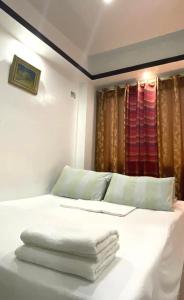 a bedroom with a white bed with towels on it at Antipolo Staycation & Transient Affordable Condo Unit By Myra in Antipolo
